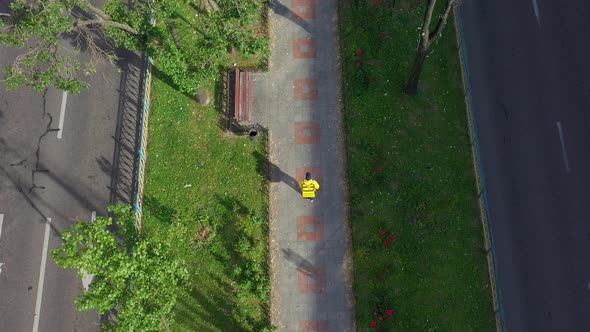 Aerial Top View of Food Delivery Courier with Yellow Uniform Walking Down the Street