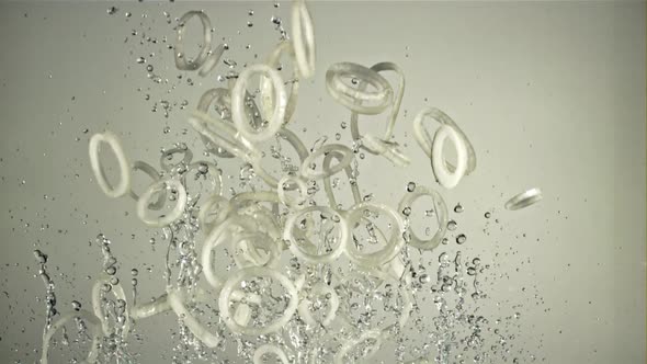 A Bunch of Onion Rings with Water Fly Up and Rotate in Flight