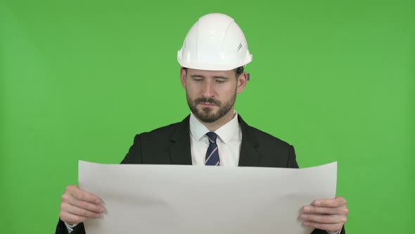 Ambitious Engineer Reading Construction Blueprint Against Chroma Key