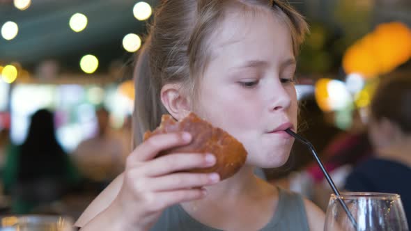 Child Girl Eating Tasty Burger in Restaurant