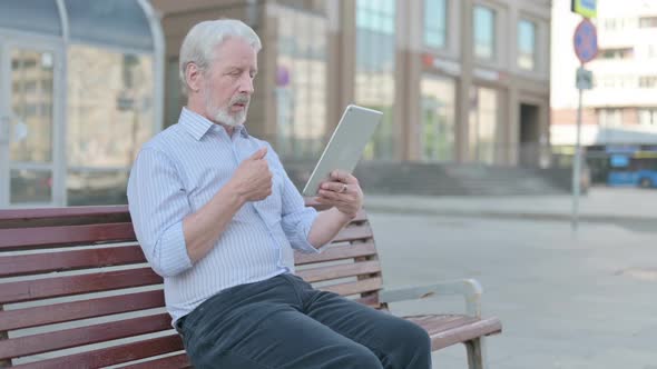 Online Video Chat on Tablet By Old Man Sitting Outdoor on Bench