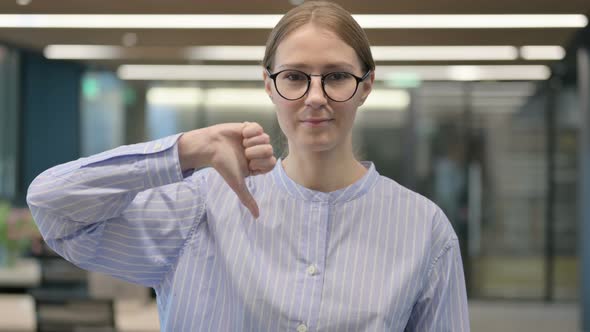 Portrait of Young Woman Showing Thumbs Down Gesture