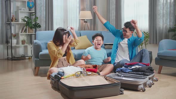 Asian Family Booking Hotel On Smartphone With Credit Card And Celebrating For A New Journey