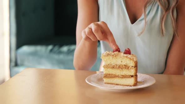 Smiling woman eating a cherry from the pastry