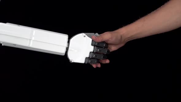 Hand of a Robot and a Man's Hand in One Handshake. Black Background. Close Up