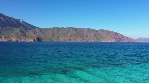 Turquoise Sea Bay with Mountains and Blue Sky in the Background