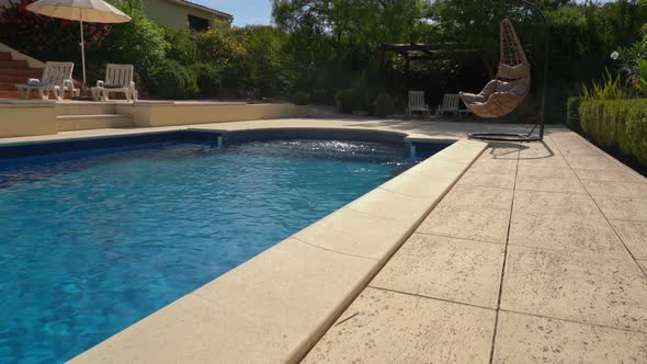 Luxurious Hanging Rocking Chair Next to the Clean Pool and Villa Residence