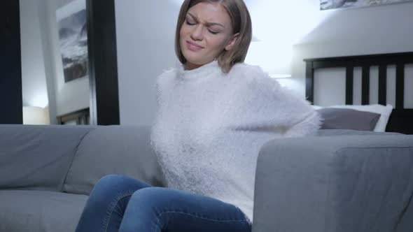 Tired Woman with Back Pain Sitting on Sofa