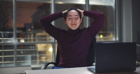 Excited Asian Businessman Looking at Laptop While Working at Night in Office