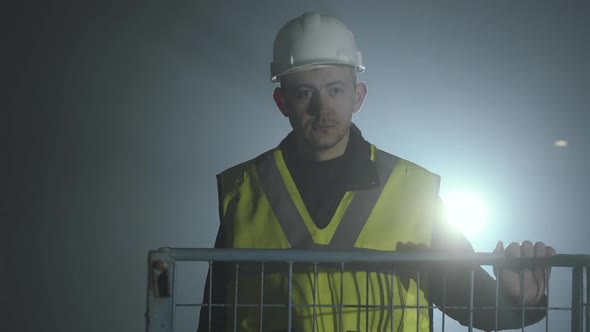 Serious Man in the Builders Uniform and Helmet Standing in Front of the Black Background with