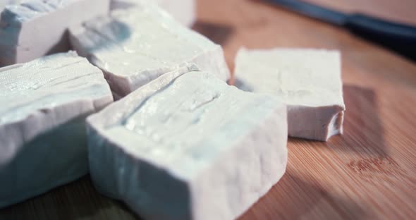 Close Interior Shot Of Big Chunks of Tofu Cubes Spinning on a Wooden Surface to the Right