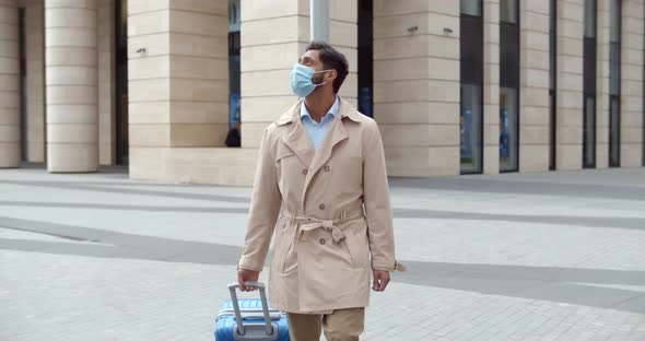 Slider Shot of Businessman with Suitcase in Face Mask Walking on Deserted Street in City Center