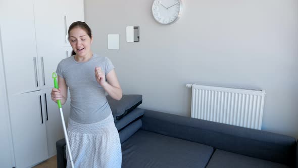 Happy Woman is Washing Floor Using Mop Singing a Song and Dancing in Her Modern Flat