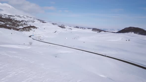 Aerial view of a car on winter road in the forest. Winter landscape countryside in Montenegro