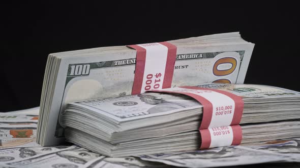 Bundles of Dollars Lying on a Pile of Money and Rotate on Black Background