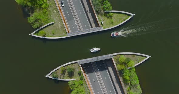 Small White sail boat passing above highway traffic at Aquaduct Veluwemeer, Harderwijk, The Netherla