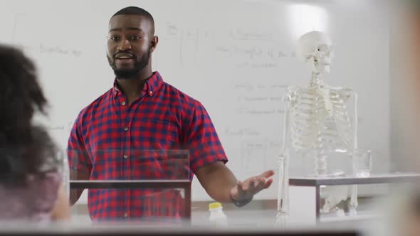 Video of happy african american teacher with class of diverse pupils during anatomy lesson