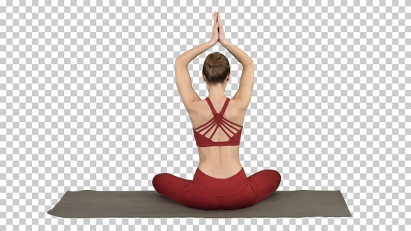 Young sporty woman sitting in lotus pose join hands above