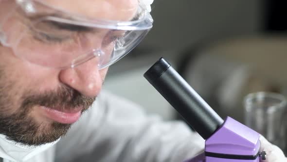 Scientist in laboratory looking through microscope and change magnification