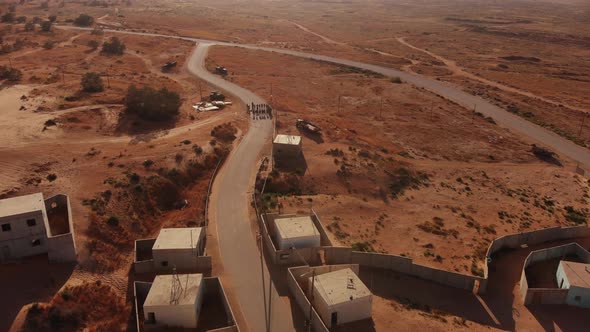 aerial shot of army troops soldiers standing in the empty road in the middle of the endless desert.