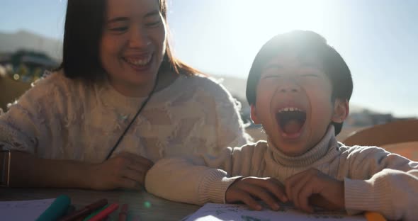 Happy asian young mother having tender moment with her child outdoors in summer sunny day