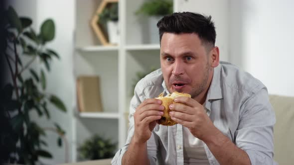 Mid-Aged Man Eating Burger and Watching TV at Home