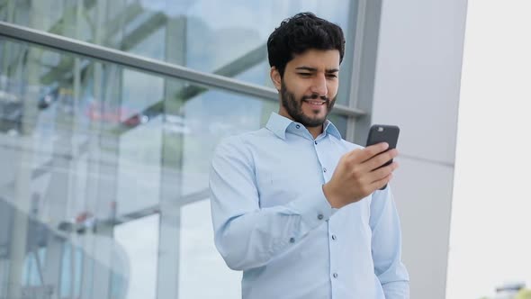 Handsome Man Using Phone Near Business Center On Street