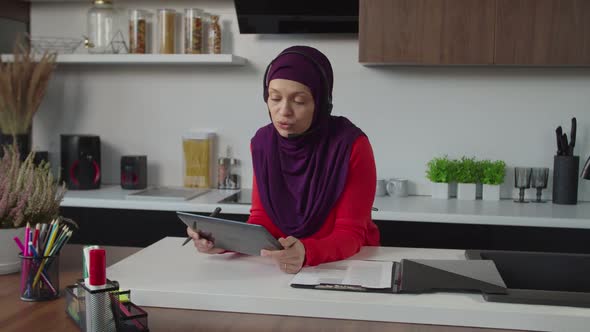 Successful Pretty Arab Businesswoman in Hijab with Headset Making Video Call on Tablet Pc Indoors