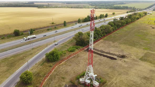 Cell Site of Tower with 5G Base Station By Highway with Traffic Move Drive Cars