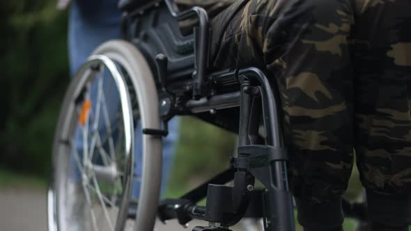 Legs of Unrecognizable African American Soldier in Wheelchair with Caucasian Woman Pushing Mobility