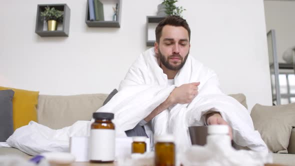 Sick Man Taking Prescription Drugs and Blowing Nose