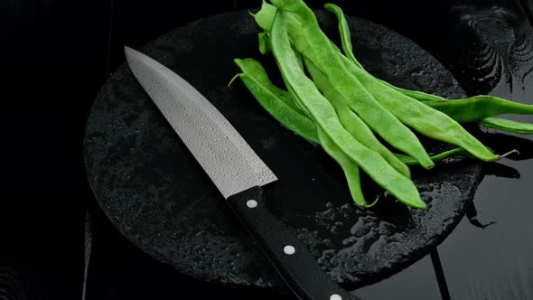 Fresh Cut Green Beans and a Knife on a Rustic Black Wooden Table