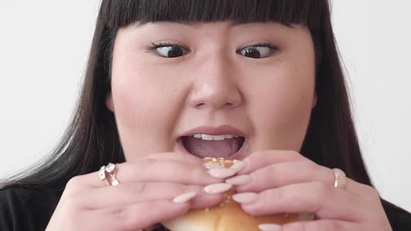 Girl Plus Size Model Eats a Hamburger and Smiles. Cute Asian Girl Nibble a Delicious Juicy Burger