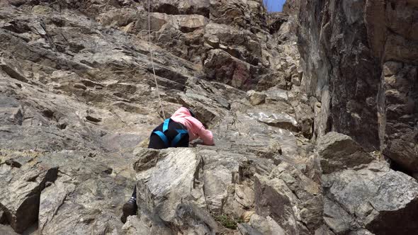 Girl is Engaged in Rock Climbing on a Steep Cliff