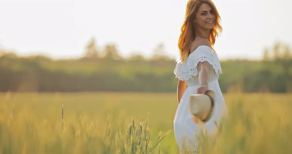 Beautiful Girl in White Dress Whirls in the Summer Field