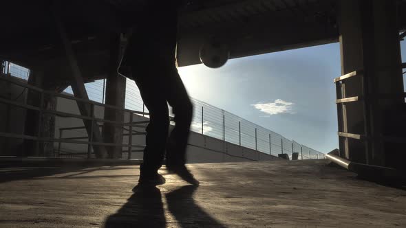 Football Freestyle. Young Man Practices with Soccer Ball in Parking and Roof