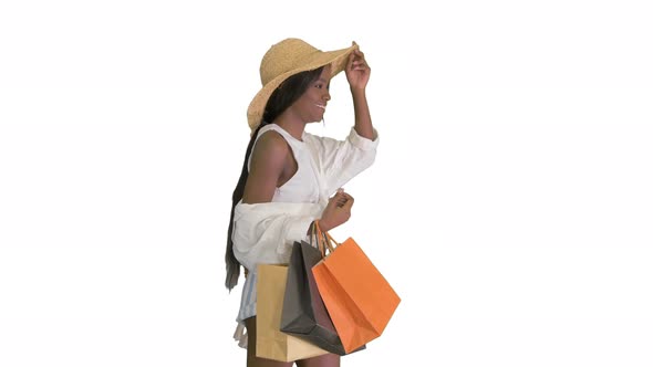 Happy African American Woman in Straw Hat Walking with Shopping Bags on White Background