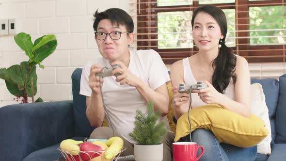 asian family husband and wife enjoy quality time with game console tv monitor challenge together