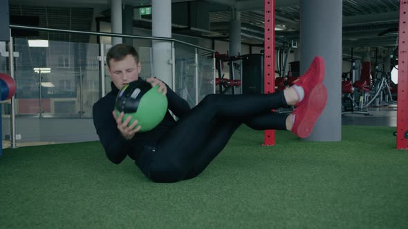 Young man is engaged in crossfit, doing leg exercises, warming up, in the gym.