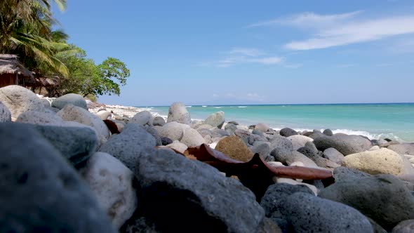 Stunning remote exotic tropical island, beach hut and pebbled beach with turquoise ocean, perfect de