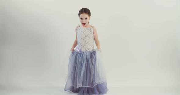 Little girl wearing a dress dances on a white studio background