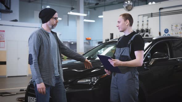 A Mechanic at a Service Station Hands Over a Finished Car to a Customer