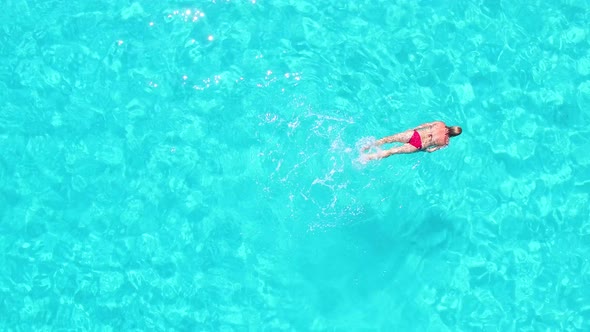 Aerial view of an attractive woman doing breast stroke in crystal clear sea