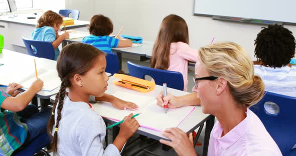 Teacher helping kids with their homework in classroom