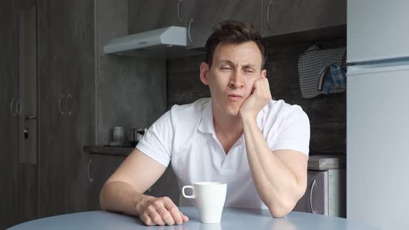 Sleepy Man Yawns and Wants to Sleep Over Cup of Coffee