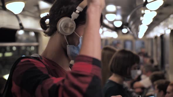 Young Man in Headphones and Face Mask in Metro Car