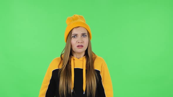 Portrait of Modern Girl in Yellow Hat Is Upset, Waving Her Hands in Indignation. Green Screen