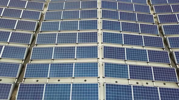 Aerial view of solar power plant with blue photovoltaic panels mounted of industrial building roof.