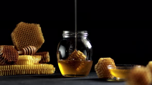 Honey dripping, pouring from honey dipper in wooden bowl