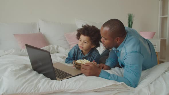 Family with Popcorn Streaming Movie Online on Bed alt